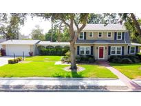 Charming two-story home featuring a red front door, lush landscaping, and a detached garage with breezeway at 708 32Nd W St, Bradenton, FL 34205