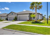 Attractive home exterior with a gray facade, a double garage, and vibrant landscaping at 8541 Whispering St, Sarasota, FL 34240
