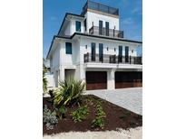 Beautiful three-story home featuring a modern design with balconies and dark wood garage doors at 2809 Avenue E, Holmes Beach, FL 34217