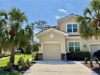 Beige two-story home with a tile roof and a two-car garage framed by lush palm trees and manicured landscaping at 3120 Oriole Dr # 101, Sarasota, FL 34243