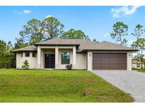 Beautiful single-story home featuring a modern architectural style, a two-car garage and a well manicured lawn at 4661 Forlano Cir, North Port, FL 34291