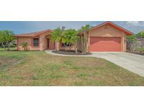 Inviting single-story home featuring an attached garage, landscaped yard, and mature palm trees at 5004 32Nd E St, Bradenton, FL 34203