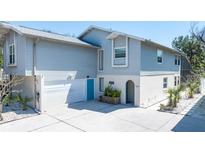 Two-story home features an attached garage, blue doors, white accents, and a well-maintained yard at 5385 Avenida Del Mare, Sarasota, FL 34242