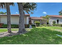 Charming single-story home with a well-maintained lawn, mature trees, and a red tile roof at 6096 Wilshire Blvd # 9, Sarasota, FL 34238