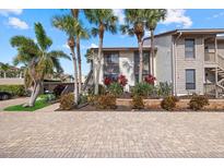 Inviting condo featuring lush landscaping, brick paved entrance and swaying palm trees on a sunny day at 6204 Midnight Pass Rd # 201, Sarasota, FL 34242