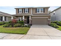 Charming two-story home featuring a well-maintained lawn, two car garage, and decorative stone accents at 6356 Mighty Eagle Way, Sarasota, FL 34241