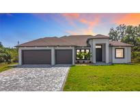 Beautiful exterior of home with a three car garage, brick driveway, and well manicured front lawn at 7152 Bougainvillea St, Englewood, FL 34224