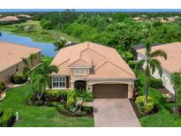 Beautiful one-story home with lush landscaping, tile roof, and brick paved driveway overlooking a pond at 8911 Heritage Sound Dr, Bradenton, FL 34212