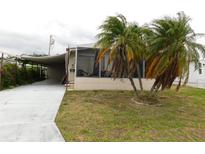 Tan home with palm trees, screened patio and covered car port at 1212 45Th E Ave, Ellenton, FL 34222