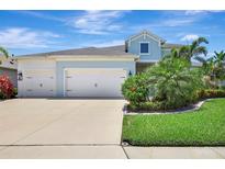 Charming two-story home with a three-car garage and lush landscaping against a brilliant blue sky at 13918 Old Creek Ct, Parrish, FL 34219