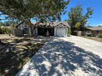 Charming exterior featuring a white-painted home, long driveway and mature trees at 1500 Crest Dr, Englewood, FL 34223