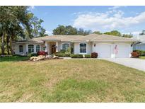 Inviting single-story home featuring a well-manicured lawn, beige exterior, and two-car garage at 2067 Tocobaga Ln, Nokomis, FL 34275