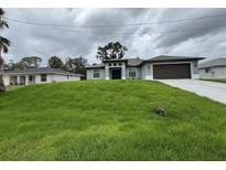 Beautifully landscaped home featuring a well-maintained lawn and modern architectural details at 2881 Pope St, North Port, FL 34287