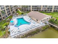 Aerial view of the community pool, showing lounge chairs, tables with umbrellas, and access to the waterfront at 3702 Lake Bayshore K-412 Dr # 412, Bradenton, FL 34205