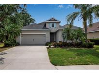 Charming single-Gathering home featuring a well-manicured lawn, mature palm trees, and a two-car garage at 5036 Brickell Park Cv, Bradenton, FL 34211
