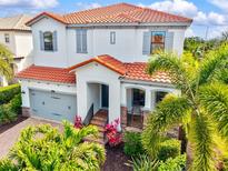 Two-story home featuring a red tile roof, gray shutters, a two car garage, and tropical landscaping at 5823 Title Row Dr, Bradenton, FL 34210