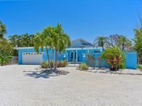 Charming single-story blue home with a well-manicured front yard and rock landscaping with palm trees at 5920 Gulf Of Mexico Dr, Longboat Key, FL 34228