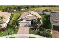 Lovely aerial view of home with clay tile roof, lake view, and beautiful landscaping in tropical community at 5987 Snowy Egret Dr, Sarasota, FL 34238