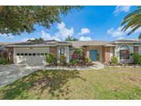 Charming home featuring a blue front door, well-manicured lawn, and beautiful landscaping with plenty of foliage at 7984 Glenbrooke Ln, Sarasota, FL 34243