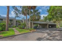 Condo building with carport and lush landscaping including palm trees and green lawns at 107 Woodland Pl # 107, Osprey, FL 34229