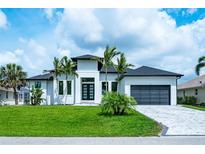 Beautiful modern home with lush lawn, palm trees, dark roof, and paver driveway at 117 Marker Rd, Rotonda West, FL 33947