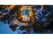 Stunning aerial view showcasing a luxurious home with a backyard pool, complemented by manicured landscaping and ambient lighting at 26 Sandy Hook S Rd, Sarasota, FL 34242