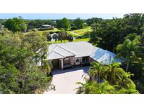 Stunning home with a paver driveway and lush landscaping, with golf course and pond views in the background at 3362 Charles Macdonald Dr, Sarasota, FL 34240