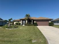 Charming single-story home with a well-maintained lawn, decorative palm trees and a two car garage at 40 Mariner Ln, Rotonda West, FL 33947