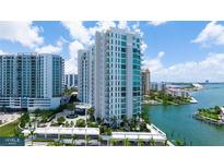 Stunning condo building with blue-tinted windows, lush landscaping, and a tranquil waterfront view at 555 Quay Cmn # 801, Sarasota, FL 34236