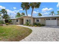 Charming single-story home featuring a brick driveway, a two-car garage, and mature landscaping at 602 Baronet Ln, Holmes Beach, FL 34217