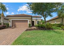 Charming single-story home with a well-manicured lawn, brick driveway, and a two-car garage at 9769 Highland Park Pl, Palmetto, FL 34221
