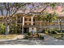 Inviting condo building featuring lush landscaping, mature trees, and convenient parking at 104 Capri Isles Blvd # 207, Venice, FL 34292