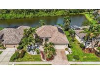 Beautiful aerial view of a home and lush landscaping with a lake in the background at 10523 Old Grove Cir, Bradenton, FL 34212