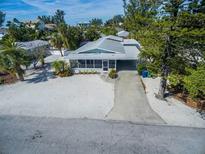 Charming single-story home with a concrete driveway surrounded by mature trees and a sandy yard at 112 Palm Ave, Anna Maria, FL 34216