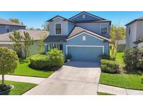 Charming two-story home featuring lush landscaping, a well-manicured lawn, and an attached two-car garage at 5033 Brickwood Rise Dr, Wimauma, FL 33598