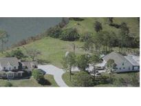 An aerial view of the home with its long driveway, and the lush yard and lake surrounding it at 60 Sinclair Dr, Sarasota, FL 34240