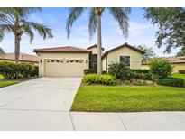 Charming single-story home features a well-manicured lawn, two-car garage, and lush tropical landscaping at 8118 Stirling Falls Cir, Sarasota, FL 34243