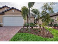 Charming single-Gathering home with a well-manicured lawn, brick driveway, and white garage door at 12091 Firewheel Pl, Venice, FL 34293