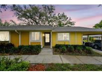Charming single-story home with yellow exterior, manicured landscaping, and a convenient carport at 1930 Peppermill Dr, Clearwater, FL 33763