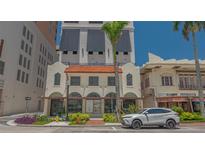 Charming building with a terracotta roof and arched windows, complemented by lush landscaping and a modern vehicle at 33 S Palm Ave # 1303, Sarasota, FL 34236