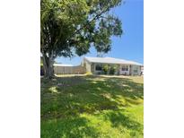 Charming single-story home with a metal roof, lush green lawn, and mature shade tree at 5094 Bunyan St, Sarasota, FL 34232