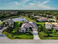 Gorgeous aerial view of a single-Gathering home with lush landscaping, a pond, and a tile roof at 13115 Harriers Pl, Bradenton, FL 34212
