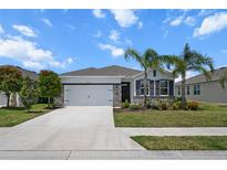 Charming single-story home with a two car garage, stone accents, palm trees and a well-manicured lawn at 13915 Mount Laurel Trl, Bradenton, FL 34211