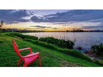 Breathtaking lake view at sunset from lush green lawn with a relaxing chair at 17728 Polo Trail, Lakewood Ranch, FL 34211