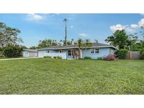 Charming single-story blue home with a white fence, lush green lawn, and welcoming curb appeal at 2825 Pinecrest St, Sarasota, FL 34239