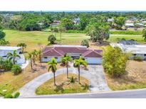 Expansive single-story home with a red tile roof, surrounded by lush greenery and a circular driveway at 3432 Pine Valley Dr, Sarasota, FL 34239