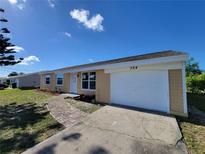 Charming single-story home with a well-manicured lawn, attached garage, and brick walkway at 354 Lasayette Ne Dr, Port Charlotte, FL 33952