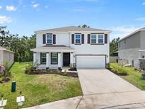 Attractive two-story home featuring a manicured lawn, front porch, two-car garage, and complementary dark shutters at 4015 Quiet Rain Ct, Palmetto, FL 34221