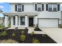 Charming two-story home with a well-manicured lawn and a welcoming front porch, garage, and decorative shutters at 4015 Quiet Rain Ct, Palmetto, FL 34221