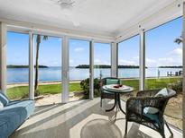 Bright sunroom with panoramic water views, wicker furniture, and a ceiling fan for optimal comfort at 4310 Falmouth Dr # 105, Longboat Key, FL 34228